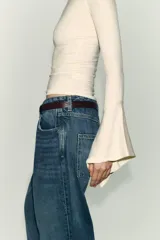 Camiseta de cuello redondo y manga larga, confeccionada en tejido rib con mezcla de lyocell. Presenta un diseño ajustado con terminación de volantes en los puños y bajo recto.