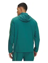 Campera de entrenamiento Under Armour Challenger, color verde esmeralda con detalles en amarillo neón. Presenta media cremallera frontal, capucha, bolsillo frontal con cierre y puños elásticos. Diseño técnico con tecnología repelente al agua y forro de malla.