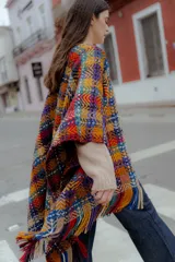 Ruana tejida multicolor con diseño geométrico y flecos.