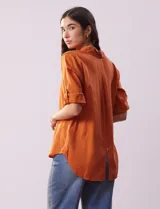 Camisa color beige de tencel, marca Hester & Orchand, con cuello con solapa, escote en V, abertura central con botones y bolsillos delanteros. Las mangas son largas y regulables con presilla y botón.