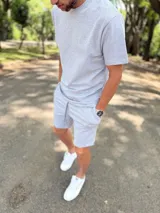 Conjunto deportivo gris melange compuesto por remera de manga corta y short con cordón ajustable en la cintura.