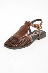 Sandalias de cuero marrón, con puntera cerrada de diseño trenzado, empeine liso y tira ajustable con hebilla en el talón. Cuenta con suela plana y baja.