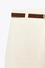 Pantalón de jean color crudo, de tiro alto, corte wide leg cropped y cinturón marrón.