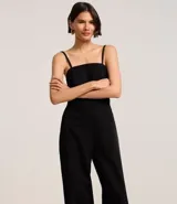 Mono largo color blanco, de breteles finos y escote recto. Presenta recorte cut-out en la cintura y lazo en la espalda.