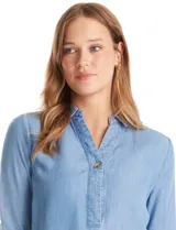 Blusa de lyocell color azul con efecto denim, cuello camisero con solapa y escote en V con cierre de un botón. Presenta mangas largas con terminación doblada y ruedo redondeado.