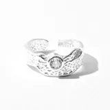 Anillo plateado con textura irregular y una circonita engarzada en el centro.