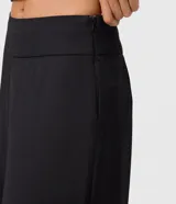 Pantalón sastre negro tipo pantalona, de corte amplio y tiro alto, con cintura lisa, pliegues frontales y cierre lateral invisible.