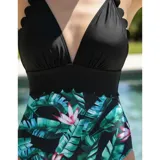 Malla enteriza bicolor de diseño combinado, con parte superior lisa en color negro de escote en V pronunciado con bordes ondulados, y parte inferior con estampado botánico de hojas verdes y flores rosadas sobre fondo negro. Cuenta con tirantes finos regulables.