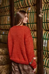 Sweater tejido a mano con lana color ladrillo, cuello redondo, puños y ruedo acanalados con rayas blancas. Presenta bordados con figuras de personas y animales.