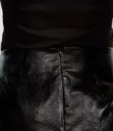 Minifalda negra de cuero sintético con textura y cierre trasero con cremallera.