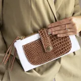 Billetera de cuero blanca con apliques de cuero marrón con textura croco. Tiene bolsillo frontal con botón, dos bolsillos con cierre y dos espacios para tarjetas.