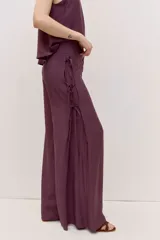 Pantalón de calce amplio y caída suelta, color bordó, con cintura alta y detalle de tiras laterales. Su silueta es oxford.