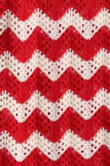 Pantalón tejido en punto jacquard estilo crochet, con diseño de rayas en zigzag de colores rojo y blanco, de tiro medio y piernas amplias.