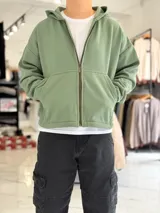 Campera verde militar con capucha, cierre frontal completo y bolsillos estilo canguro, de corte boxy fit.
