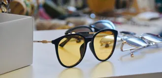 Lentes de sol con montura redonda color negro y lentes amarillos.