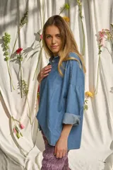 Camisa de denim suave, de corte oversize, con mangas largas abombadas, puños doblados y cierre frontal con botones nacarados.