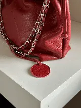 Cartera tipo bolso capitoneada de cuero color negro, con asa de cadena plateada y cuero entrelazado. Forrada por dentro y con bolsillo interno.