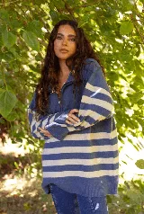 Buzo de lana merino con diseño a rayas horizontales en azul y blanco, cuello alto con cierre frontal y mangas largas.