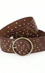 Cinturón marrón de cuero sintético con tachas y ojalillos metálicos dorados y hebilla circular dorada.