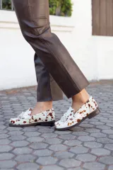 Mocasines de cuero con estampado animal print de vaca, hechos a mano en Uruguay.