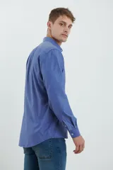 Camisa azul de manga larga con cuello clásico, cierre con botones y bolsillo en el pecho.
