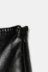 Falda pantalón negra de tiro alto con efecto piel desgastado y abertura frontal. Presenta costuras visibles en el centro y laterales.