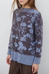 Buzo de tejido de punto con cuello redondo, mangas largas con puños acanalados y diseño estampado de flores en tonos rojos.