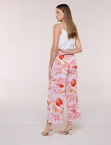 Pantalón crop de lino y rayón, con diseño wide leg de corte holgado, estampado tropical de hojas en tonos verde, azul y marrón sobre fondo blanco. Cuenta con pretina trasera elastizada y bolsillos delanteros.
