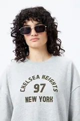 Buzo negro de corte holgado con estampado frontal que dice "Chelsea Heights 97 New York".