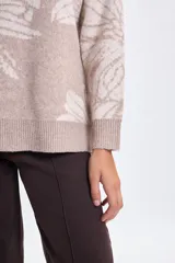 Buzo de punto con diseño jacquard de flores en tonos beige y crema, de corte holgado, cuello redondo y mangas largas con puños acanalados.