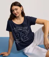 Remera de algodón azul marino con cuello redondo y mangas cortas. Presenta un diseño gráfico en el frente con el texto 'TEAM OF 92' y detalles de estrellas estampadas en contorno blanco.