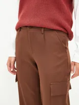 Pantalón cargo de corte recto y tiro medio, color marrón, con bolsillos laterales con solapa y cierre frontal con botón y cremallera.