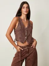 Top estilo chaleco crop de denim marrón con efecto acid wash, escote en V, cierre frontal con botones metálicos y cordones ajustables en los laterales.