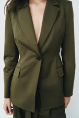 Blazer verde militar entallado con cuello de solapa, manga larga, cierre frontal de un botón y bolsillos con solapa.