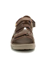 Sandalias Caterpillar modelo Cadent para hombre, color marrón, fabricadas con capellada de cuero y textil con detalles de nailon. Cuentan con múltiples tiras ajustables con velcro, plantilla de espuma EVA y suela de goma con ranuras para mayor tracción.