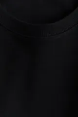 Remera de punto interlock pesado color negro, con cuello redondo ribeteado en canalé, mangas cortas y bajo recto.
