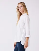 Camisa blanca de algodón con corte clásico y silueta oversize, cuello con solapa y botones ocultos. Mangas tres cuartos con terminación doblada y tajo. Laterales con tajo y botones funcionales. Largo de espalda mayor al largo delantero. Espalda con canesú y pliegue central.