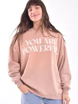 Buzo de cuello redondo y manga larga, color marrón, con estampado gráfico frontal en color lila que incluye texto y personajes animados.