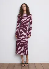 Vestido midi evasé con estampado animal print tipo cebra en tonos bordó y rosado, cuello redondo y manga larga.