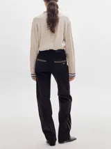 Pantalón de pana roja con corte holgado y tiro medio. Presenta una línea dorada a lo largo de la pierna.