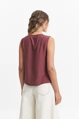 Blusa sin mangas color gris claro con textura rayada vertical y lazo ajustable en el escote.