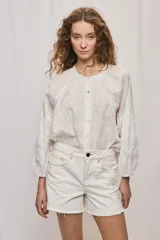 Short de denim blanco de calce recto y tiro medio, con bolsillos delanteros, cierre con botón y terminación desflecada en el ruedo. Presenta detalles florales bordados al tono en el frente.