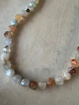 Collar de cuentas facetadas en tonos pastel como blanco, naranja, azul y gris.