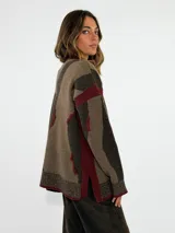Sweater de tejido de punto con diseño abstracto de rayas irregulares en tonos azul y marrón. Presenta cuello redondo, mangas largas con caída de hombro y puños y ruedo acanalados.