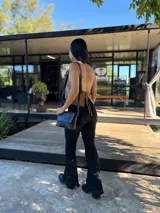 Bota corta de cuero negro con punta cuadrada y taco bloque de altura media con textura grabada. Presenta un diseño minimalista con costura central vertical y cierre lateral interno.