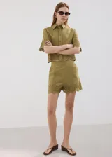 Short de tiro medio color verde militar, con pinzas, bolsillos laterales y delicados detalles bordados calados en el ruedo.