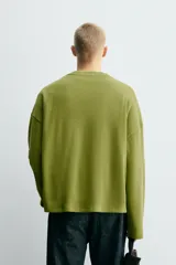 Sudadera de corte relajado, color verde oliva, confeccionada en tejido compacto de mezcla de algodón y lino. Presenta cuello redondo con acabado en rib y mangas largas.