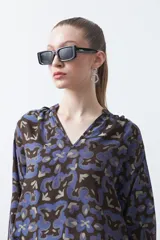 Blusa de manga larga con cuello en V y estampado abstracto en tonos azul y marrón oscuro.