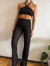 Pantalón negro de tejido calado con cintura elástica y corte acampanado.