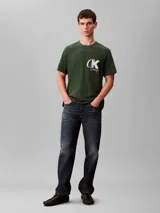 Remera de cuello redondo y manga corta, confeccionada en tejido de punto de algodón. Presenta un estampado frontal con el monograma de Calvin Klein y el logo de la marca en color blanco sobre un fondo verde oscuro.